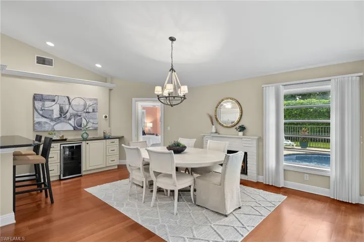 Dining area with beverage cooler, visible vents, light wood-style flooring, and lofted ceiling