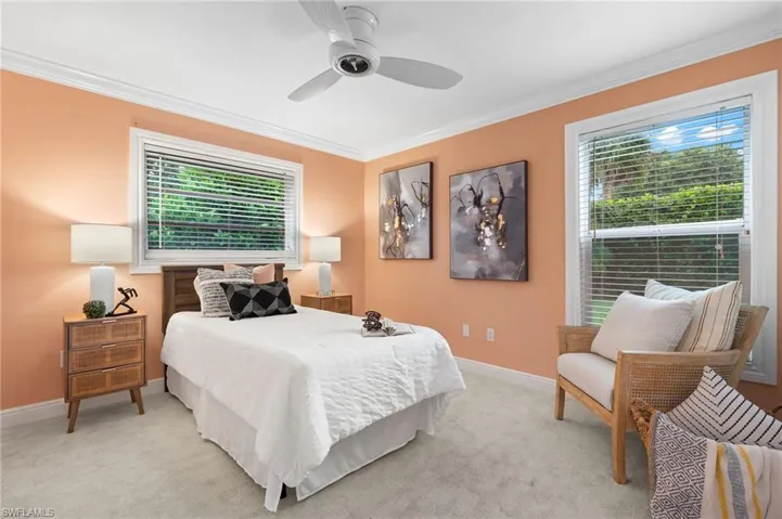 Bedroom featuring multiple windows, light colored carpet, baseboards, and ornamental molding