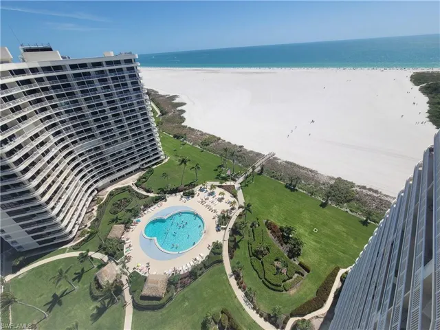 Birds eye view of property with a water view and a beach view
