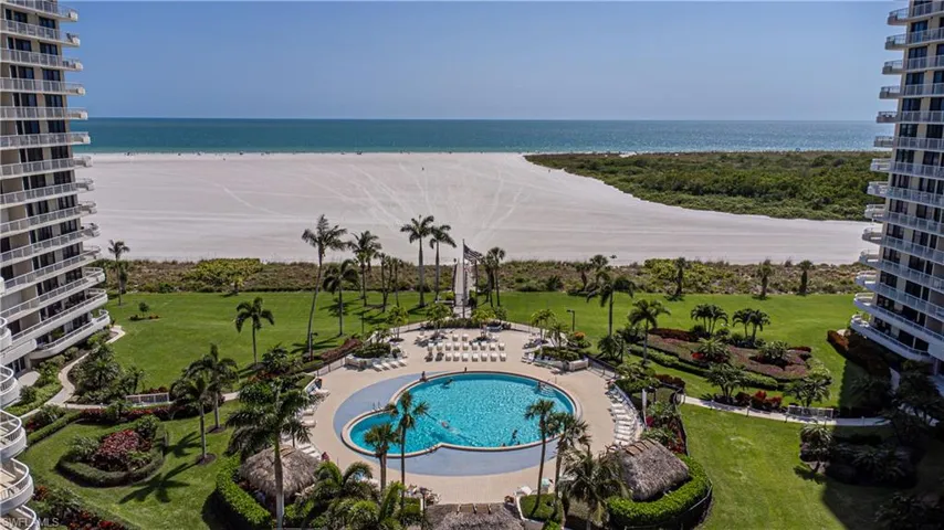 View of swimming pool featuring a patio, a water view, a beach view, and a yard