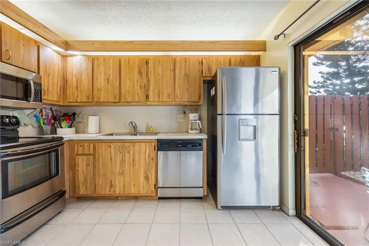 Kitchen with stainless steel appliances, light countertops, a textured ceiling, tasteful backsplash, and wood finish cabinetry