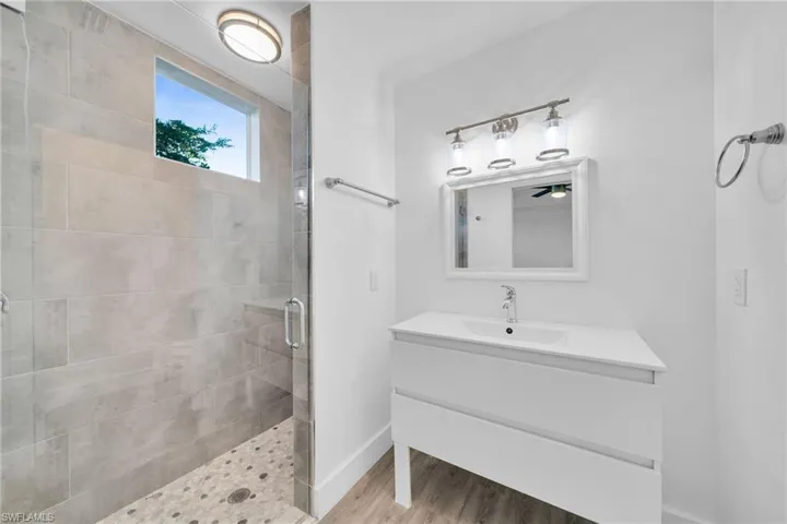 Glass-enclosed shower with a built-in bench, rectangular window, and pebble-tile flooring