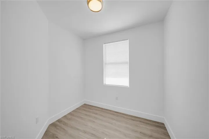 Wood-finish flooring, single window with blinds, and flush mount ceiling light