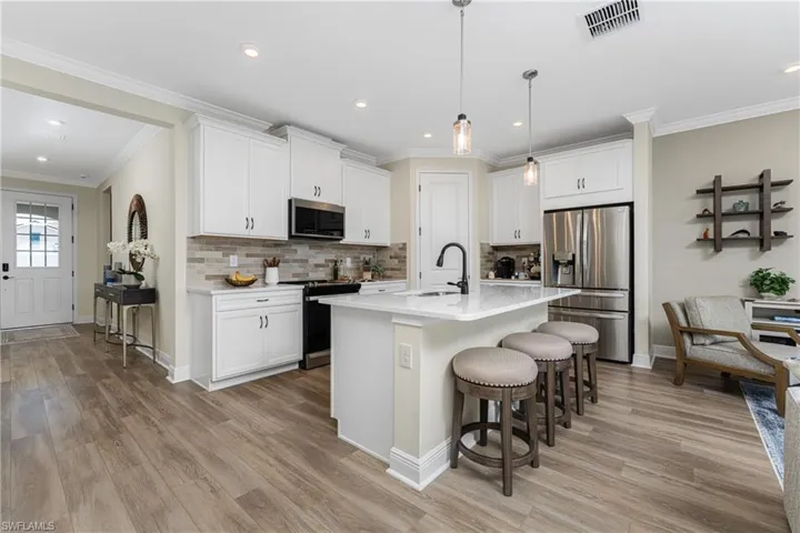 Kitchen featuring white cabinets, a kitchen island with sink, stainless steel appliances, and light hardwood / wood-style flooring