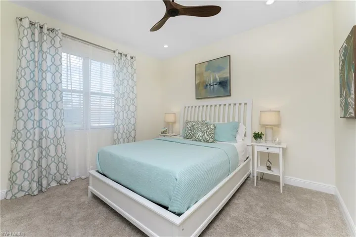 Carpeted bedroom featuring ceiling fan and multiple windows