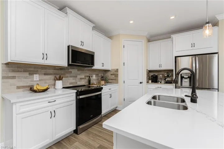 Kitchen with white cabinets, light hardwood / wood-style floors, appliances with stainless steel finishes, and sink