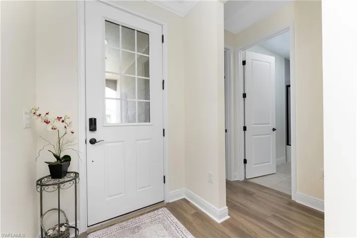 Entryway with ornamental molding and light hardwood / wood-style floors