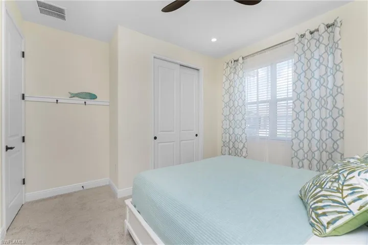 Carpeted bedroom with ceiling fan and a closet