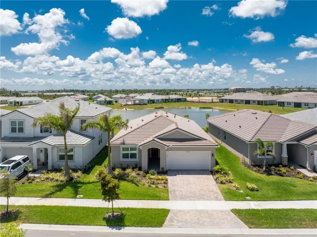 View of front of property with a garage, a water view, and a front lawn