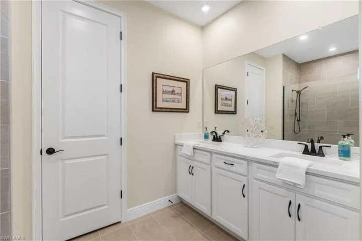 Bathroom with a tile shower, vanity, and tile patterned floors