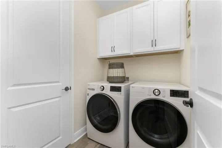 Laundry room featuring light wood-type flooring, independent washer and dryer, and cabinets