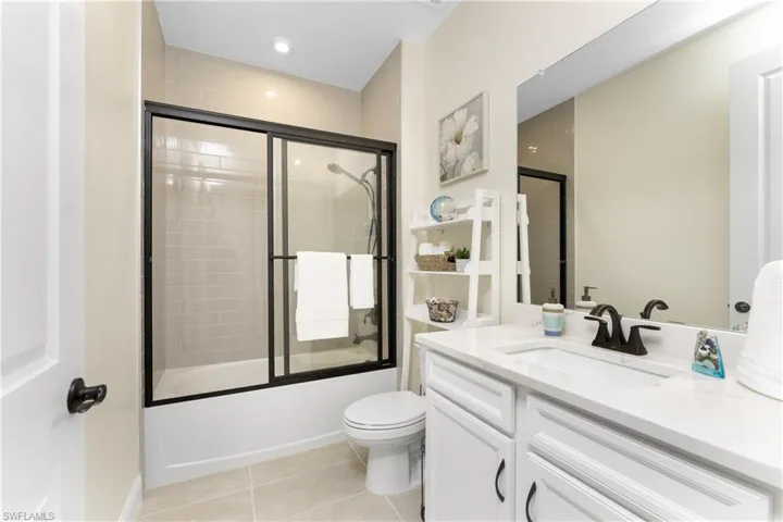 Full bathroom with tile patterned flooring, bath / shower combo with glass door, vanity, and toilet