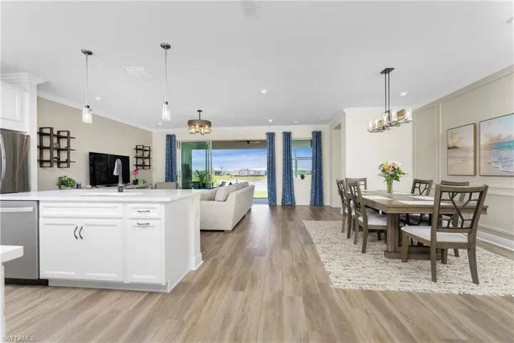 Kitchen featuring light hardwood / wood-style floors, white cabinetry, dishwasher, and pendant lighting