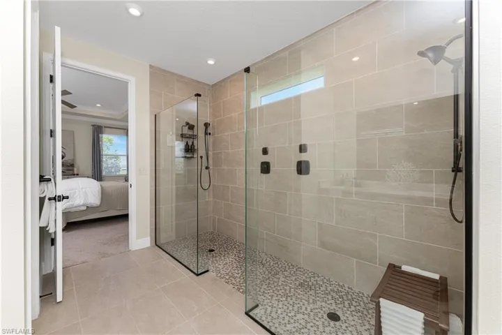Bathroom with tiled shower, ornamental molding, and tile patterned floors