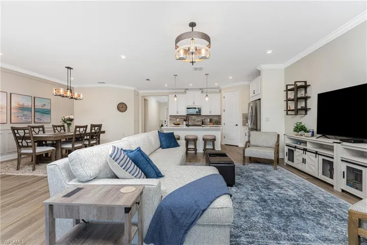Living room featuring an inviting chandelier, light hardwood / wood-style floors, ornamental molding, and sink