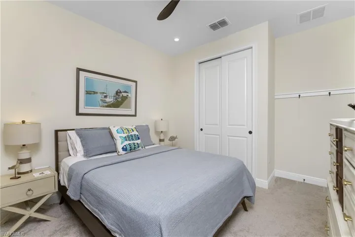 Bedroom with ceiling fan, a closet, and light carpet