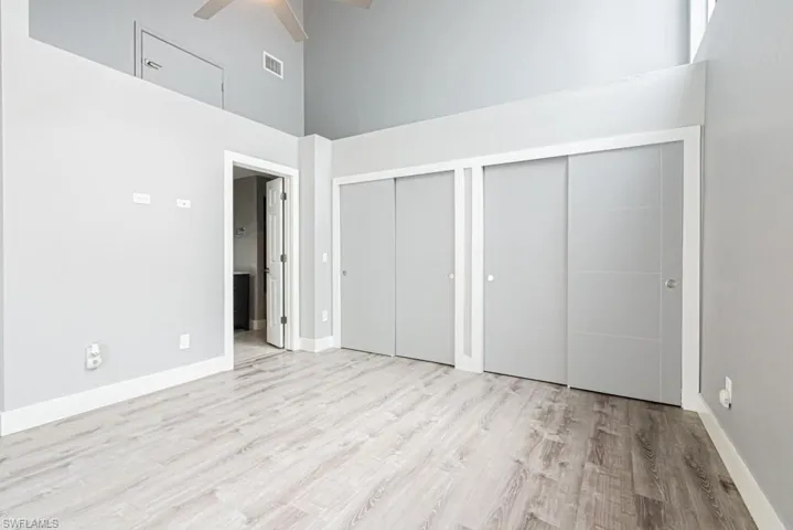 Unfurnished bedroom featuring two closets, a high ceiling, light wood finished floors, and ceiling fan