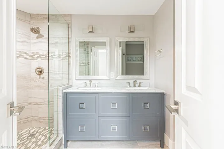 Bathroom with a stall shower, double vanity, and light tile patterned floors