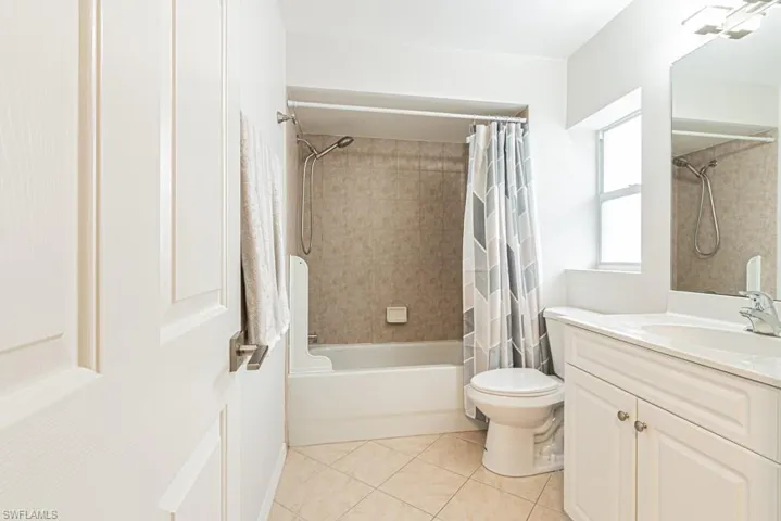 Full bathroom with shower / bath combination with curtain, vanity, and light tile patterned floors
