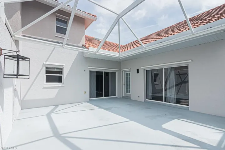 Rear view of house with a sunroom, a patio, a tiled roof, and stucco siding