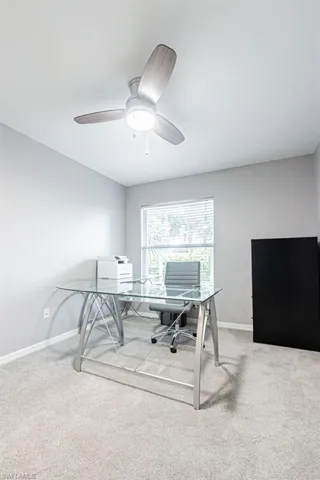 Home office/bedroom featuring light colored carpet and a ceiling fan