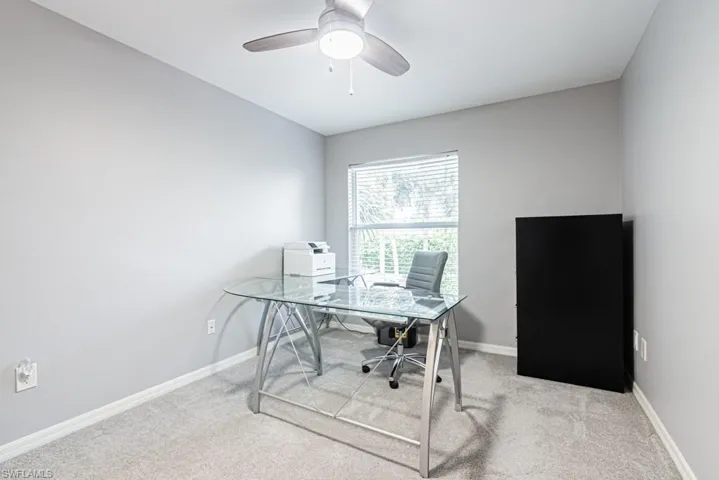 Office/bedroom area featuring a walk in closet, carpet and a ceiling fan