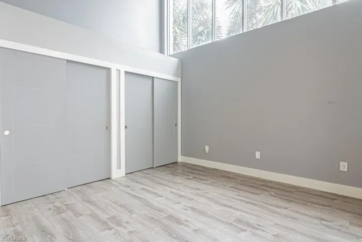 Unfurnished bedroom featuring two closets, light wood finished floors, and a towering ceiling