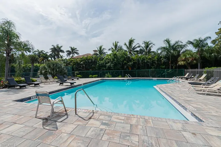 Community pool featuring a patio area and view of wooded area