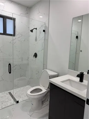 Bathroom featuring vanity, toilet, and a shower with door