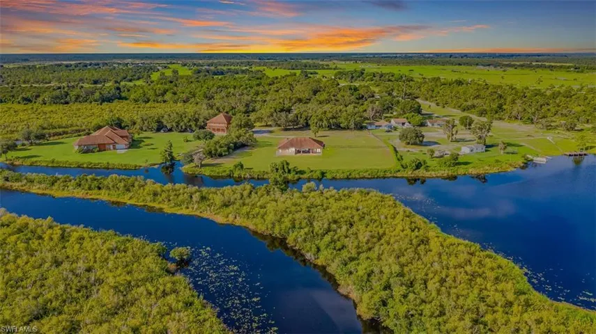Drone / aerial view of a main house, guest house, forest and a large body of water