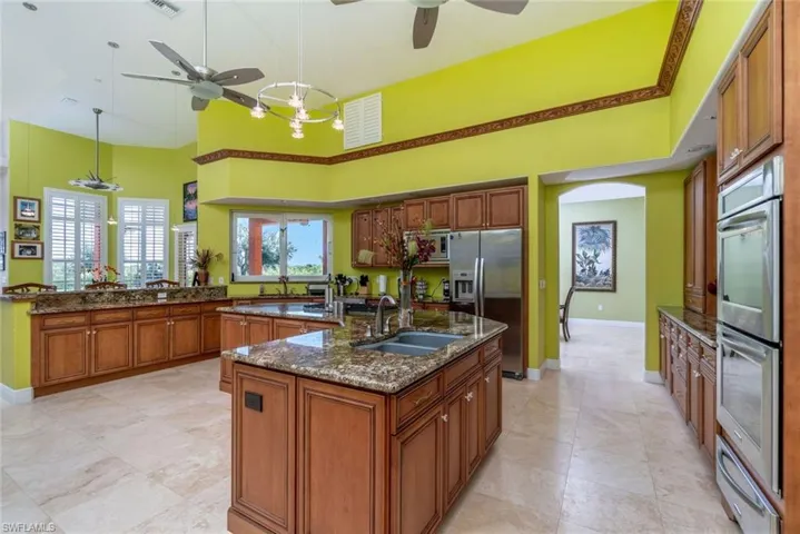 Gourment kitchen with double ovens, double sinks, high cabinets, granite tops, plant shelf, ceiling fans