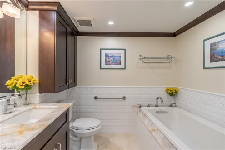 Guest Bathroom featuring vanity, tiled tub, crown molding, tile patterned flooring, and toilet