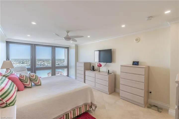 Primary bedroom with ceiling fan and ornamental molding