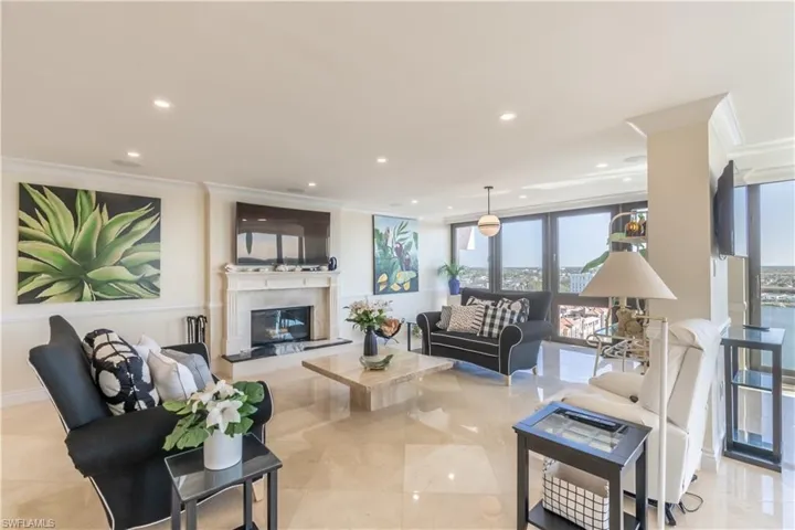 Living room with baseboards, a premium fireplace, ornamental molding, and recessed lighting