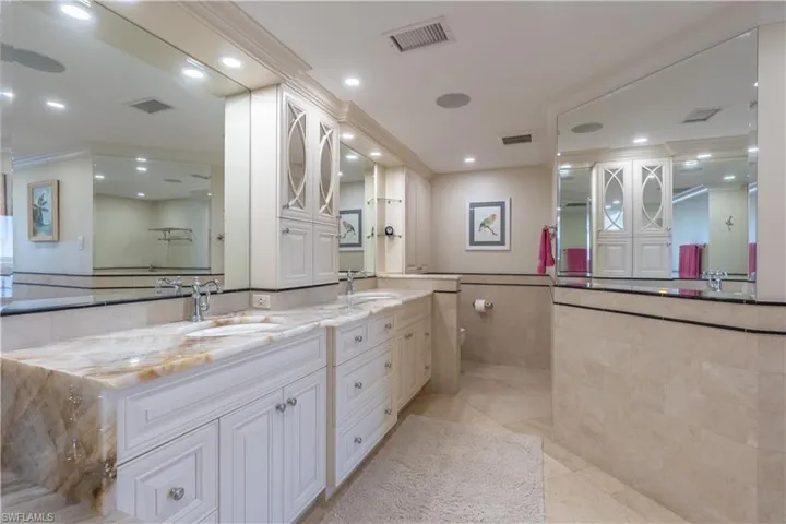 Primary Bathroom featuring tile walls, vanity, crown molding, and tile patterned flooring
