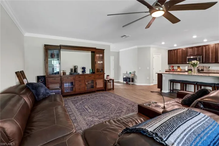 Living room featuring ceiling fan, ornamental molding, and wood-type flooring
