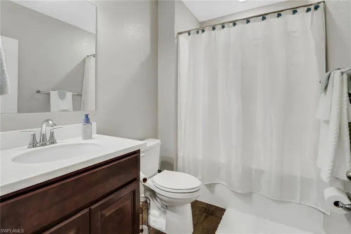 Full bathroom with shower / bath combo, wood-type flooring, toilet, and vanity