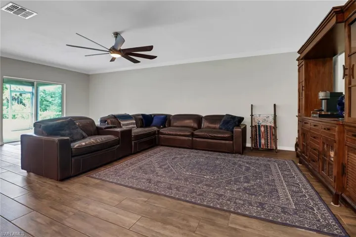 Living room with ceiling fan, ornamental molding, and dark hardwood / wood-style flooring