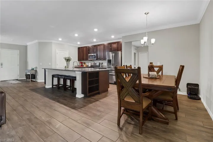 Dining area with ornamental molding, hardwood / wood-style flooring, an inviting chandelier, and sink