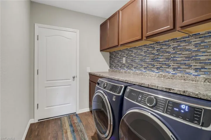 Laundry area with dark hardwood / wood-style flooring, cabinets, and washer and clothes dryer