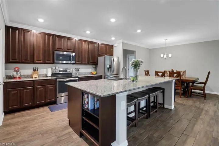 Kitchen with a kitchen island with sink, stainless steel appliances, wood-type flooring, sink, and a breakfast bar