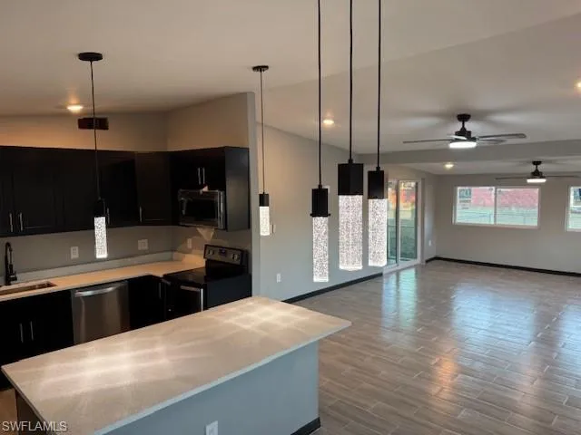 Kitchen with stainless steel appliances, hanging light fixtures, light hardwood / wood-style floors, and ceiling fan