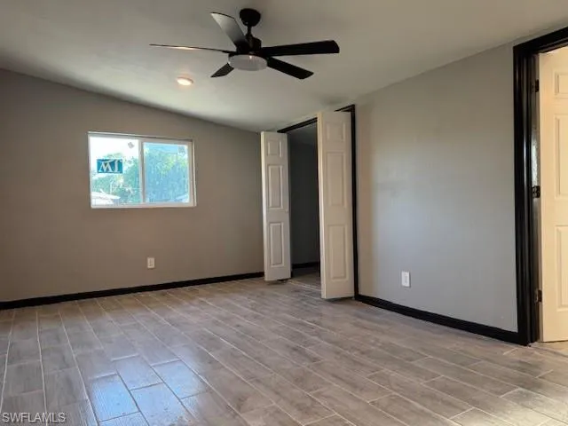 Unfurnished bedroom with light hardwood / wood-style floors, vaulted ceiling, and ceiling fan
