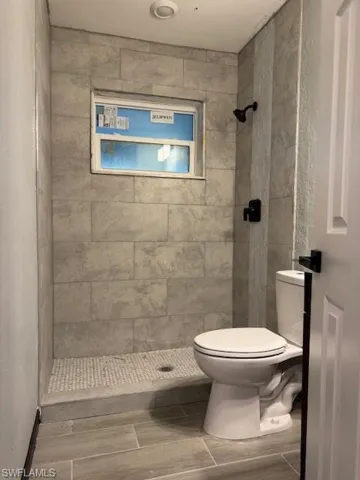 Bathroom featuring a tile shower and toilet