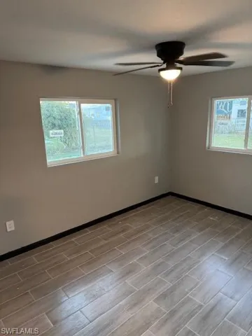 Empty room with ceiling fan, a healthy amount of sunlight, and light wood-type flooring