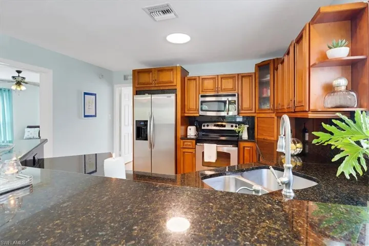 Kitchen featuring sink, tasteful backsplash, dark stone counters, ceiling fan, and stainless steel appliances