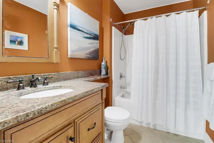 Full bathroom with tile patterned flooring, vanity, shower / tub combo with curtain, and toilet