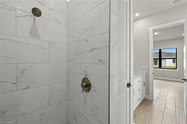 Bathroom featuring vanity, a tile shower, and wood-type flooring