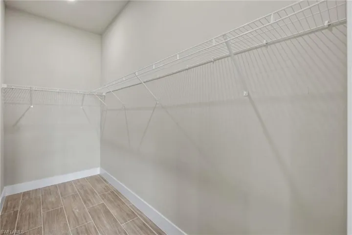 Master bedroom walk in closet with light wood-type flooring