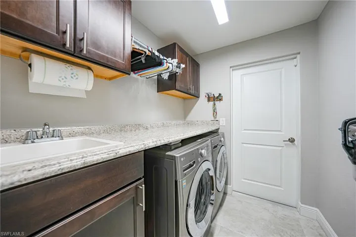 Clothes washing area with cabinet space, independent washer and dryer, and baseboards